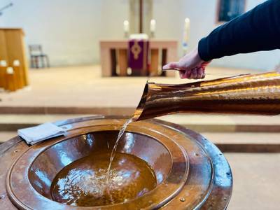 Wasser wird in Taufstein gegossen